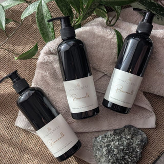 Rensemælk bottles on a textured surface with a plant and towel in the background, featuring a pump dispenser.