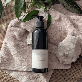 Rensemælk in a black pump bottle on a soft towel, surrounded by a crystal and green plant leaves.