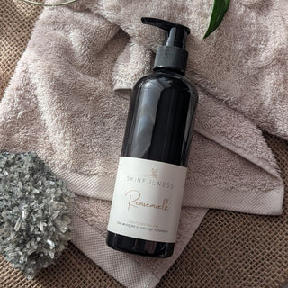 Rensemælk cleansing milk in a black pump bottle on a textured surface with towels and a plant.
